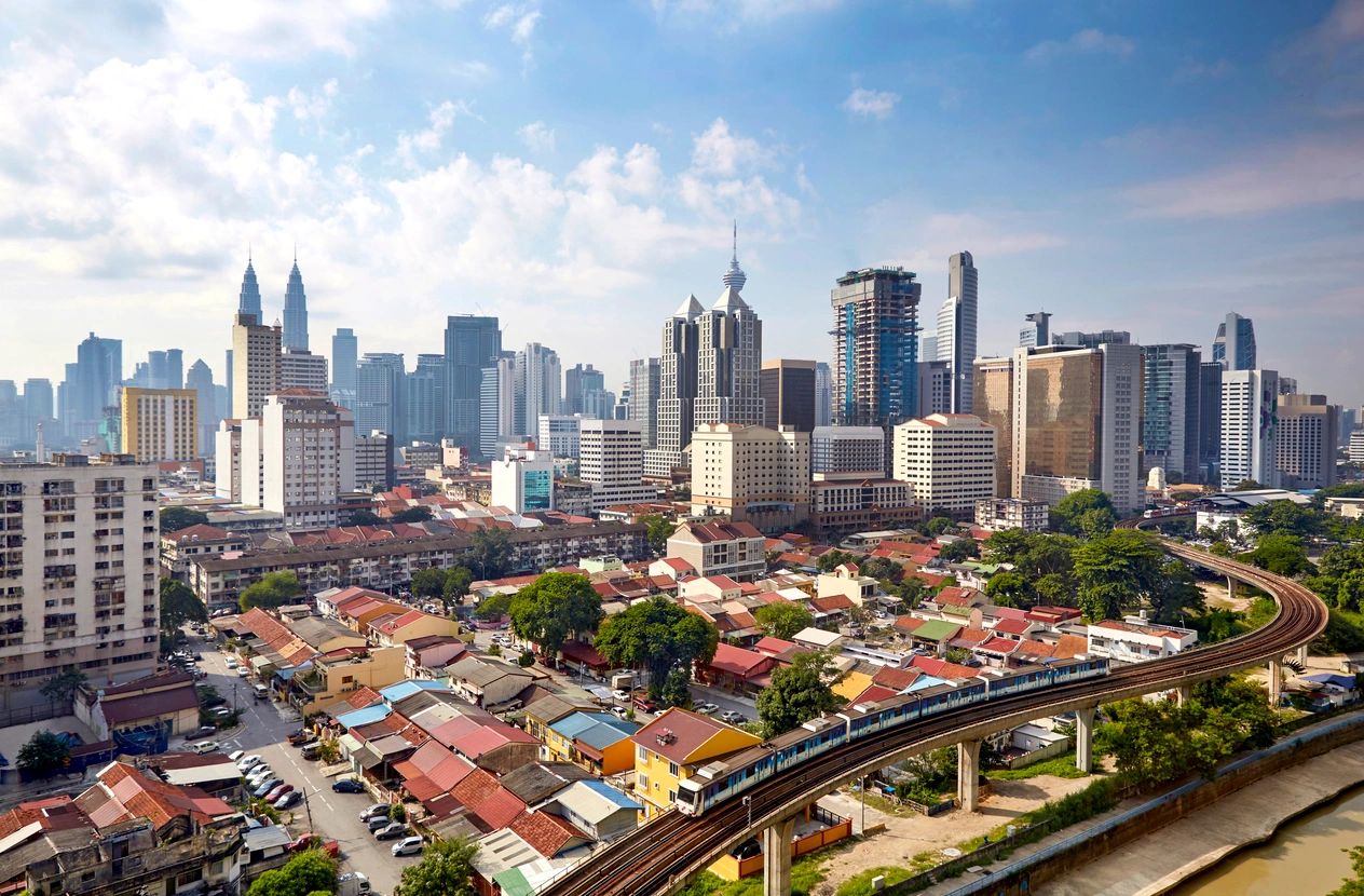 A city with many buildings and a train on the tracks.